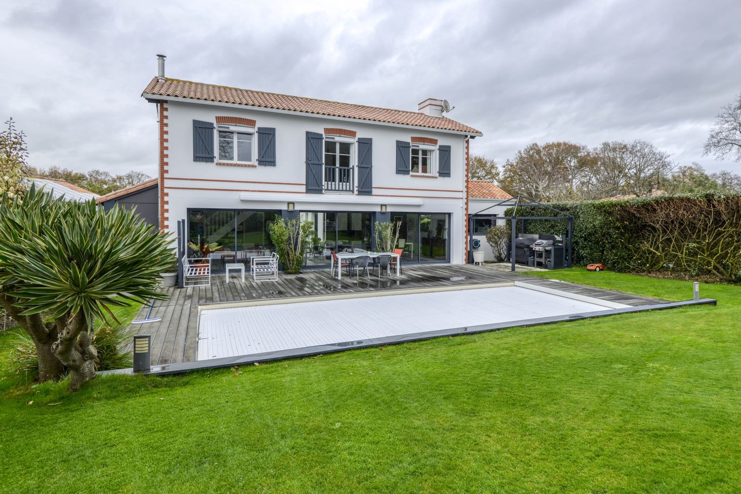 Avant : maison avec piscine bâchée sous un ciel gris
